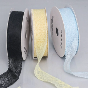 Detailed view of three rolls of scalloped floral lace ribbons in black, yellow, and blue