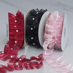 Close-up of pleated mesh lace ribbons with embedded pearls in burgundy, black and pink