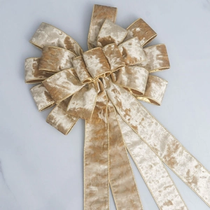 Champagne velvet Christmas bow with gold wire edges on white marble background
