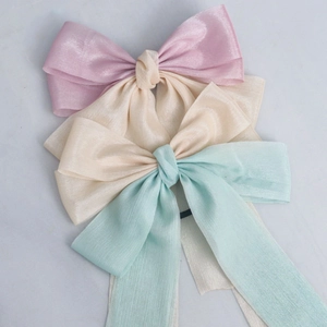 Detailed macro view of triple pastel satin and organza bow hair accessories
