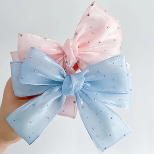 Détail de barrettes nœuds en organza rose et bleu avec décoration de strass brillants