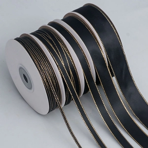 Detail view of black polyester ribbons with gold edges in various widths on white reels