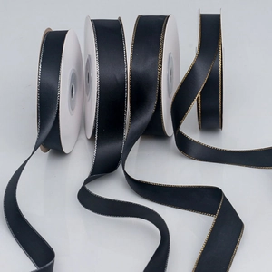 Detail of black satin ribbon with gold and silver metallic edges in four widths on white spools