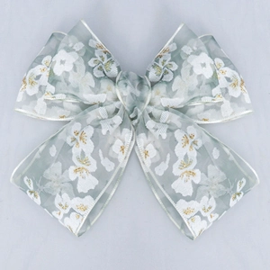 Detail of grey-green floral organza ribbon bow with gold glitter for DIY hair accessories