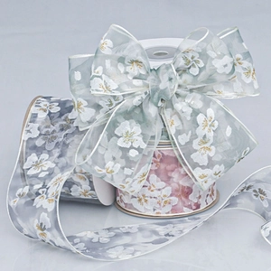 Detail of sheer floral ribbon with white cherry blossoms and gold glitter accents