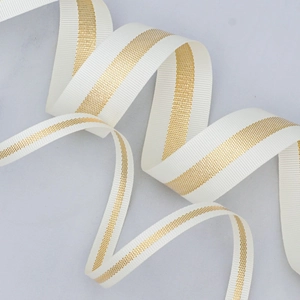 Beige grosgrain ribbon with gold metallic center stripe on marble background