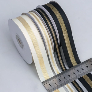 Detail of metallic gold striped grosgrain ribbon rolls in various widths on ruler