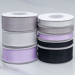 Grosgrain ribbons in grey and black showing different widths on marble surface