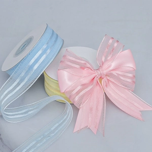Detailed view of striped organza ribbon rolls and a pink handmade decorative bow