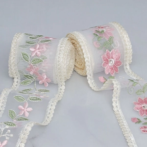 Close-up of mesh embroidery lace with pink flowers and green leaves pattern