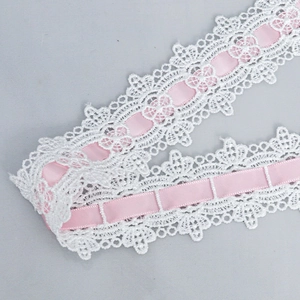 Detailed macro view of white polyester wavy hollow lace with pink satin ribbon insert