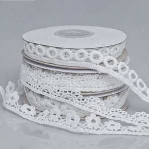 Detail of three white lace trim rolls showing hollow circles, scalloped edges and floral patterns