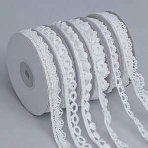 Detailed macro view of multiple white lace ribbons featuring floral and wave patterns