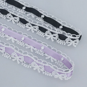 Detalle de encaje bordado con cintas de raso negro y lavanda para manualidades DIY