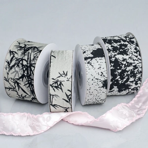 Macro shot of ink wash bamboo pattern ribbons and pink floral lace on white spools