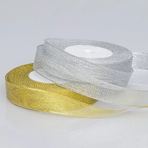 Dettaglio macro di nastri metallici oro e argento con trama intrecciata su rulli