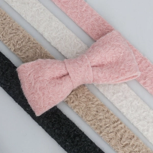 Detail of wavy flocked ribbon textures and bow clips in pink beige white and black