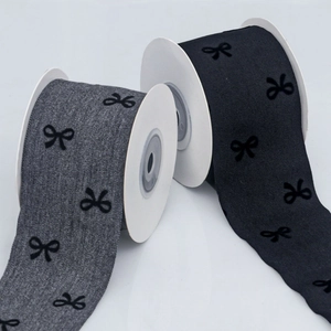 Close-up of denim and black ribbons with velvet bow patterns on white rolls
