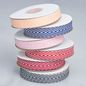 Detailed close-up of herringbone cotton ribbons in multiple colors on white spools