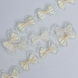 Detail of 3.5cm polyester embroidery lace with cream satin bows for doll dressmaking