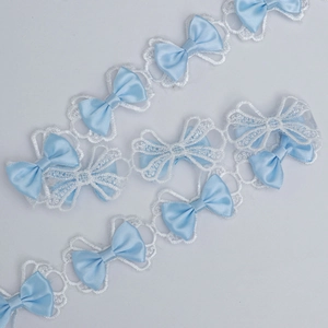Close-up of 3.5cm white polyester lace trim with light blue satin bows for DIY crafts
