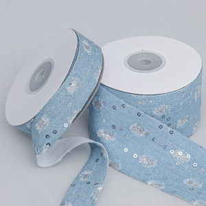 Dettaglio di nastro denim azzurro con paillettes argento e bordi sfilacciati per fai-da-te