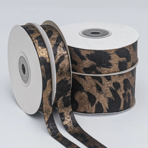 Macro shot of double-sided leopard print ribbons with gold foil texture in multiple widths