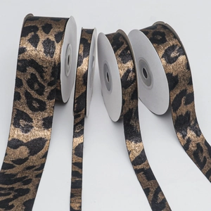 Detail showing four widths of double-sided gold leopard print ribbons on white spools