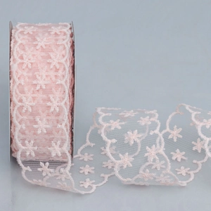 Close-up of light pink lace ribbon roll with white floral embroidery for DIY crafts
