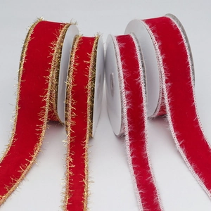 Detail of red velvet ribbons with gold fringe and white plush edges on white spools