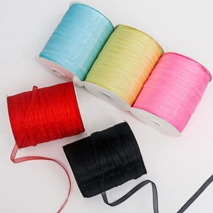 Detail of five semi-transparent chiffon ribbon rolls in blue, yellow, pink, red, and black