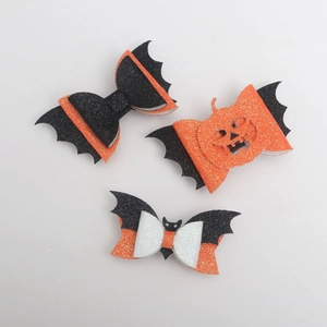 Macro detail of Halloween bow hair clips with bat wings and pumpkin designs in glitter finish