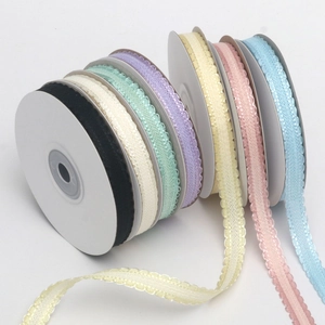 Close-up of multicolored wavy edge decorative ribbons on white spools for DIY gift packing