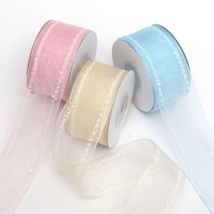 Dettaglio di nastri in organza a doppia linea in rosa, oro e blu con bordi ricamati