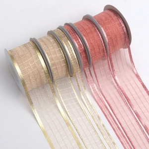 Detail of four sheer organza ribbon rolls in champagne and rose pink with metallic edges