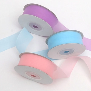 Macro detail of 2.5cm sheer organza ribbons in pastel purple, blue, and pink rolls