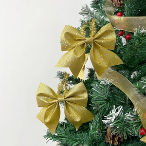 Golden glitter Christmas bow ornament hanging on a festive tree with red berries decor
