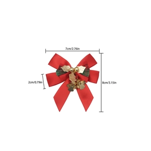 Detail view of a red satin Christmas bow with golden bells and tartan plaid accents