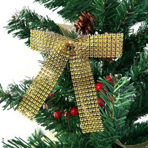 Close-up of golden sequined hollow bow ornament on a Christmas tree with festive berries