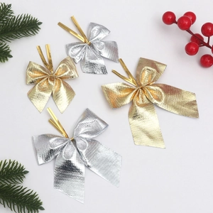 Metallic gold and silver Christmas bows with wire ties on festive pine background
