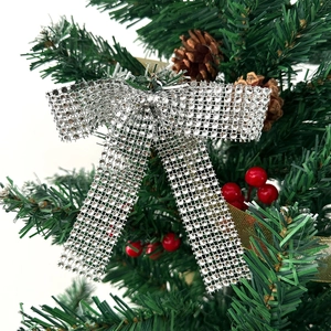 Close-up of sparkling silver rhinestone bow ornament on a Christmas tree with pine cones