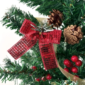 Fiocco di Natale scintillante con paillettes rosse e aghi di pino su un albero