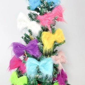 Fiocchi colorati in peluche appesi a un albero di Natale innevato per decorazioni fai-da-te