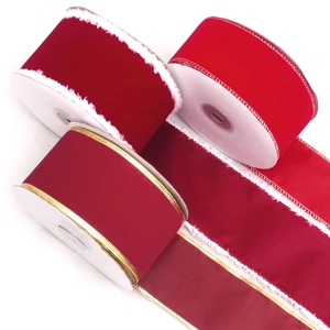 Detail of red velvet ribbons with white faux fur and gold edges on white cardboard spools
