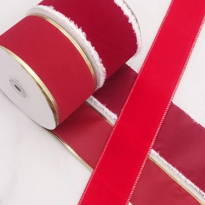 Detail of red velvet Christmas ribbon with white plush trim and gold stitched edges