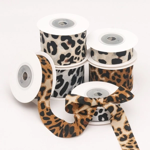 Detailed view of leopard print ribbons in yellow and grey tones on white spools