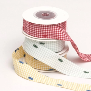 Close-up of multicolored gingham ribbons with leaf prints on white spools for DIY sewing