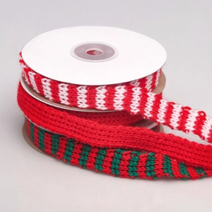 Close-up of three knitted Christmas ribbons with stripes on cardboard spools