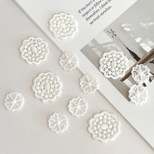 Gros plan de patchs de dentelle florale blanche avec broderie détaillée sur un bureau