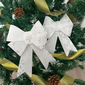 Close-up of white fabric Christmas bows with silver snowflakes on a festive tree branch